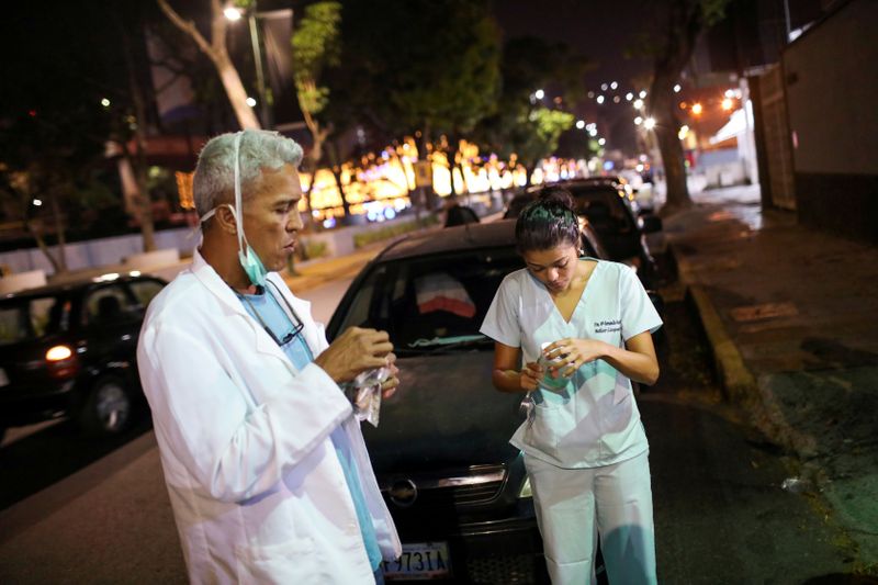 &copy; Reuters. FILE PHOTO: Doctors Carlos Martinez and Maria Martinez eat a snack while they wait in line to get fuel at a gas station, during a nationwide quarantine due to the coronavirus disease (COVID-19) outbreak, in Caracas