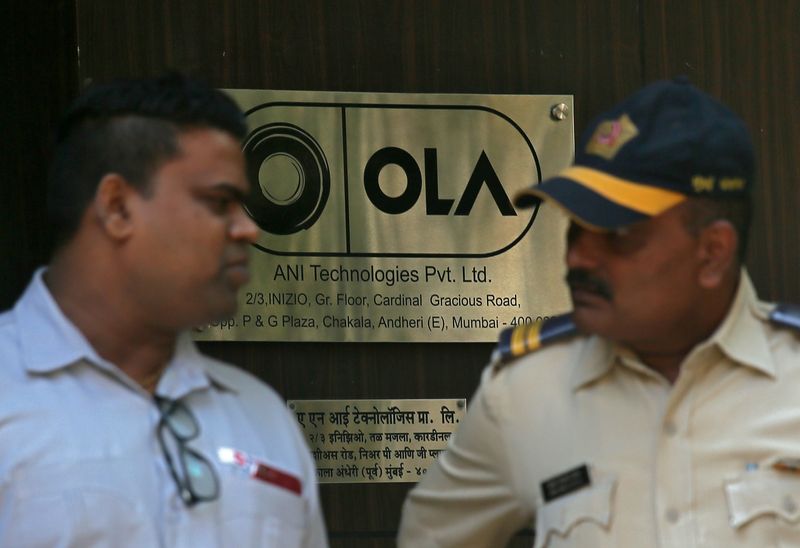 &copy; Reuters. A policeman speaks to an Ola employee outside its office in Mumbai