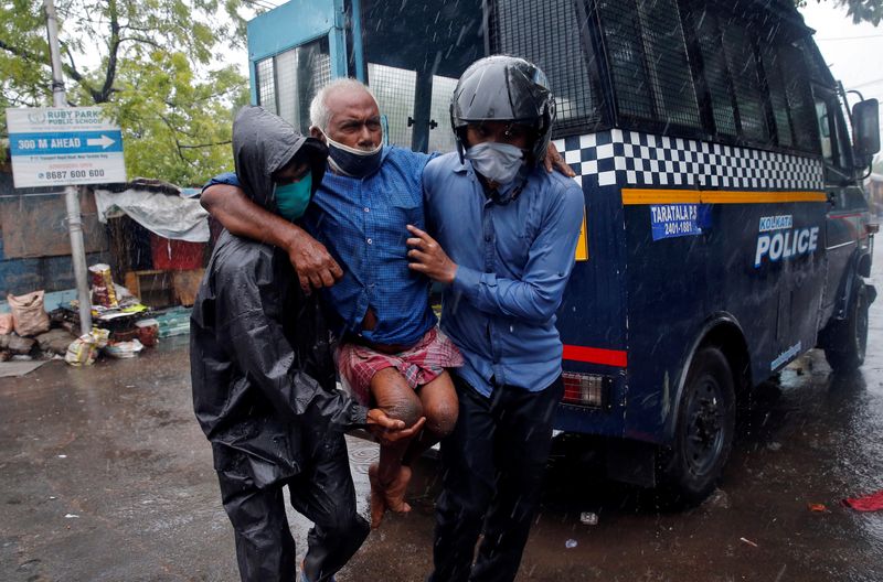 © Reuters. Police officers carry a disabled man to a safer place before Cyclone Amphan makes its landfall, in Kolkata