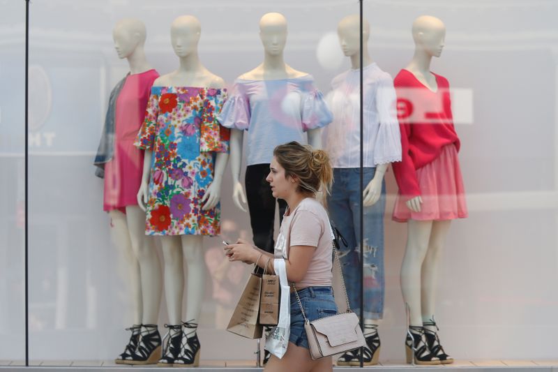 &copy; Reuters. FILE PHOTO:  A woman carries shopping bags while walking past a window display outside a retail store in Ottawa