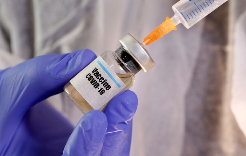 &copy; Reuters. A woman holds a small bottle labeled with a &quot;Vaccine COVID-19&quot; sticker and a medical syringe in this illustration