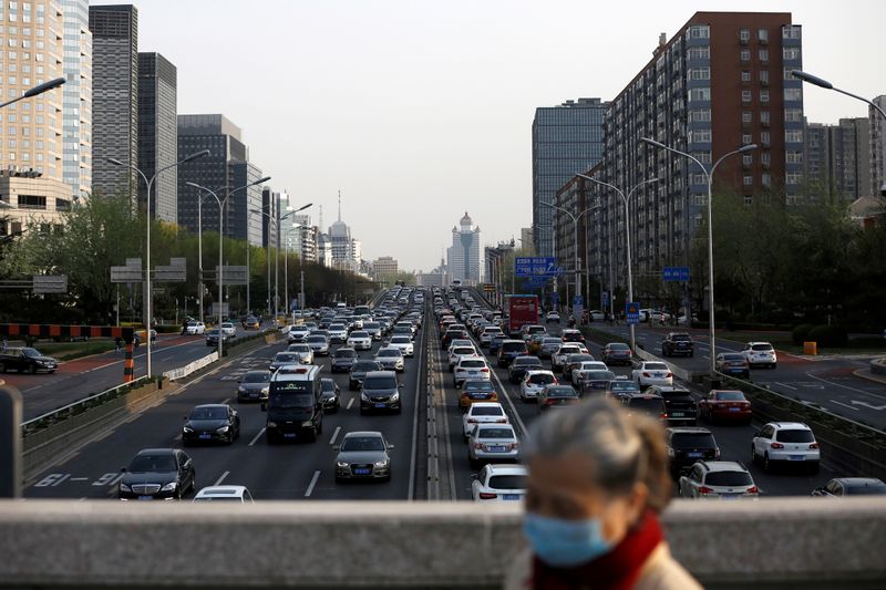 &copy; Reuters. FILE PHOTO: A woman wearing a face mask walks on a bridge as cars are seen in a traffic jam during evening rush hour in Beijing, as the country is hit by an outbreak of the novel coronavirus disease (COVID-19)