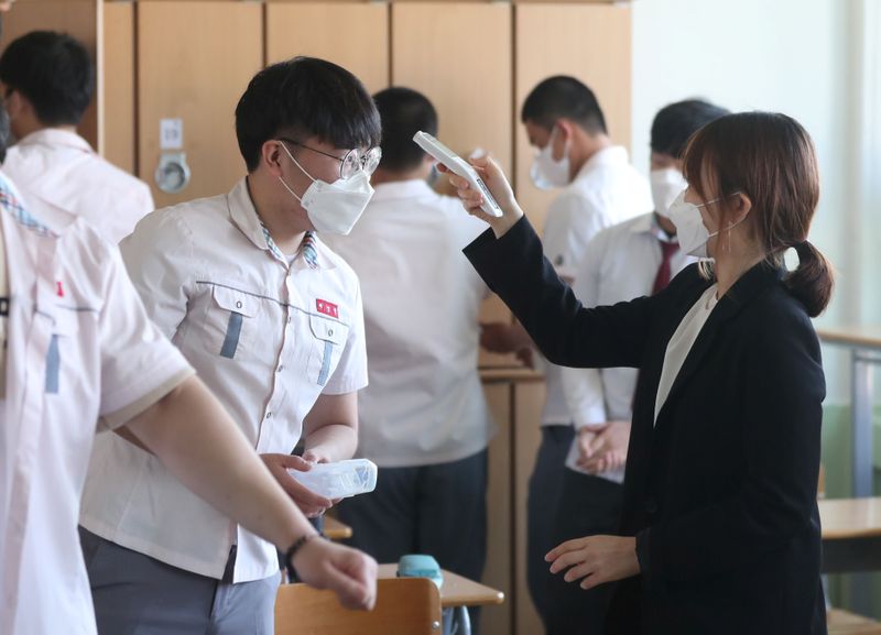 © Reuters. Aluno tem a temperatura auferida em escola de Gimhae, Coreia do Sul
