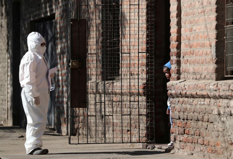 &copy; Reuters. Mulher com roupa de proteção conversa com criança imigrante em Santiago, no Chile