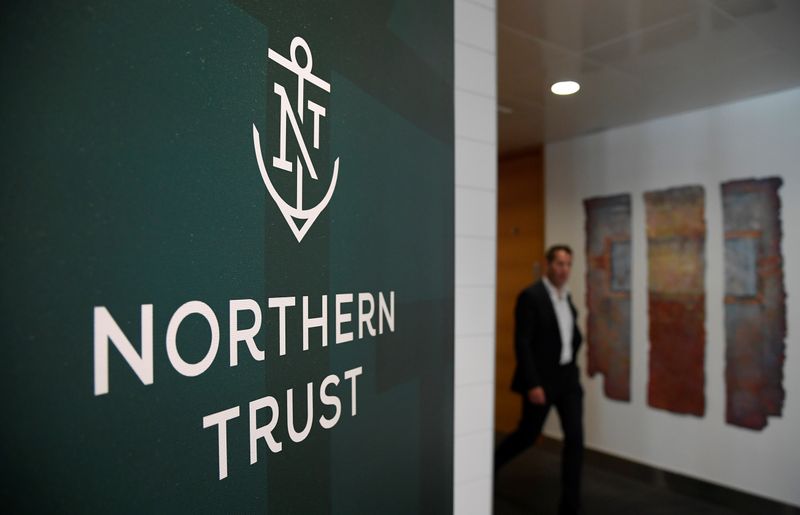 © Reuters. An employee walks past a company logo at Northern Trust offices in London