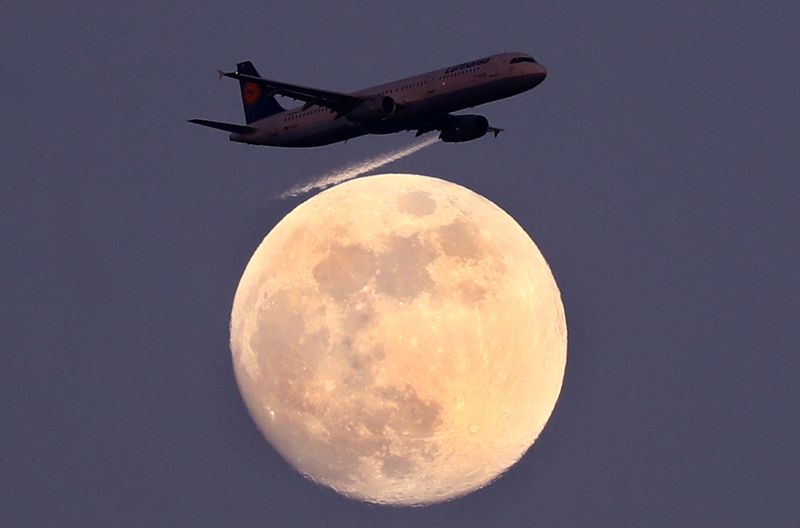 © Reuters. FILE PHOTO: An airplane of German air carrier Lufthansa passes the moon over Frankfurt