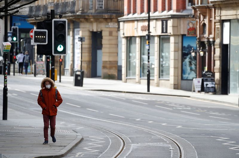 &copy; Reuters. A man wears a mask as he walks along a deserted street amid the coronavirus outbreak in Manchester, Britain