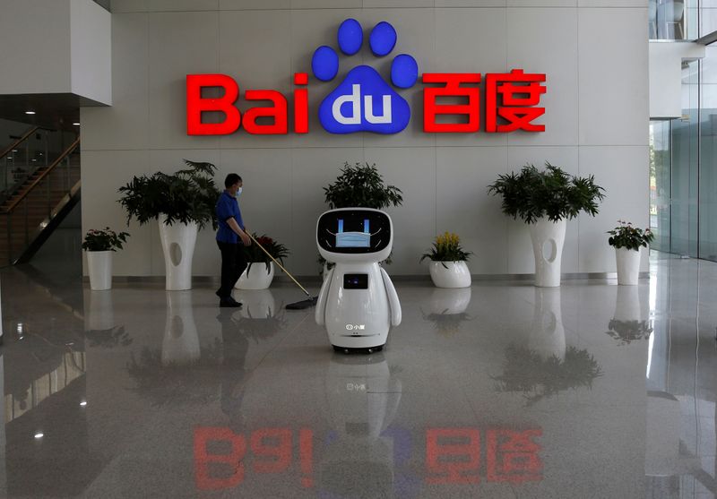 &copy; Reuters. Wworker wearing a face mask cleans the floor, near a Baidu AI robot which shows a face mask on its screen, at Baidu&apos;s headquarters in Beijing