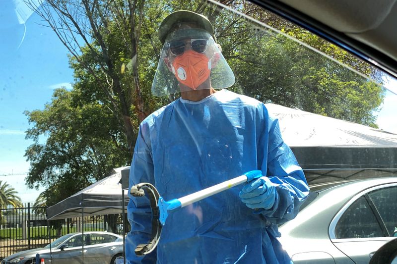 © Reuters. FILE PHOTO: A healthcare worker reaches toward a car to grab a completed coronavirus diagnostic test, as the global outbreak of the coronavirus disease (COVID-19) continues, in Los Angeles