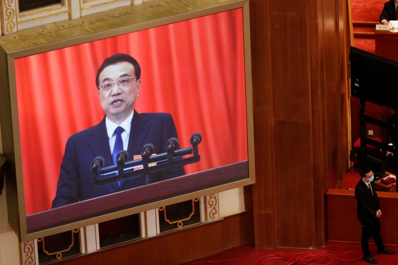 &copy; Reuters. Il premier cinese Li Keqiang durante la sessione plenaria del Congresso del partito comunista cinese trasmesso su uno schermo presso la Great Hall of the People di Pechino, 22 maggio 2020