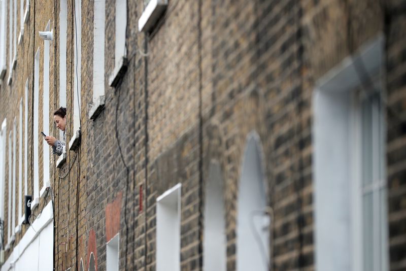 &copy; Reuters. FOTO DE ARCHIVO: Una mujer es vista usando su teléfono desde la ventana de una casa residencial en Westminster en Londres, Reino Unido, el 29 de abril de 2020