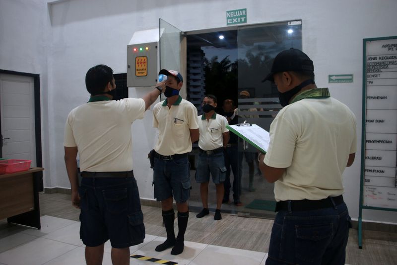 &copy; Reuters. Workers are checked with a thermal scanner before start their work to prevent the spread of the coronavirus disease (COVID-19)