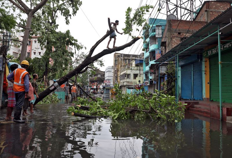 &copy; Reuters. A man cuts branches of an uprooted tree after Cyclone Amphan made its landfall, in Kolkata