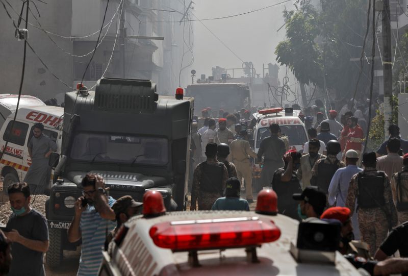 &copy; Reuters. Ambulancias y vehículos de bomberos se reúnen en el lugar del accidente de un avión de pasajeros en una zona residencial cerca de un aeropuerto en Karachi, Pakistán