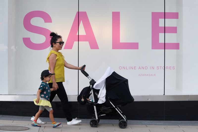&copy; Reuters. FILE PHOTO:  A woman walks with children past a sales sign on display outside a retail store in Ottawa