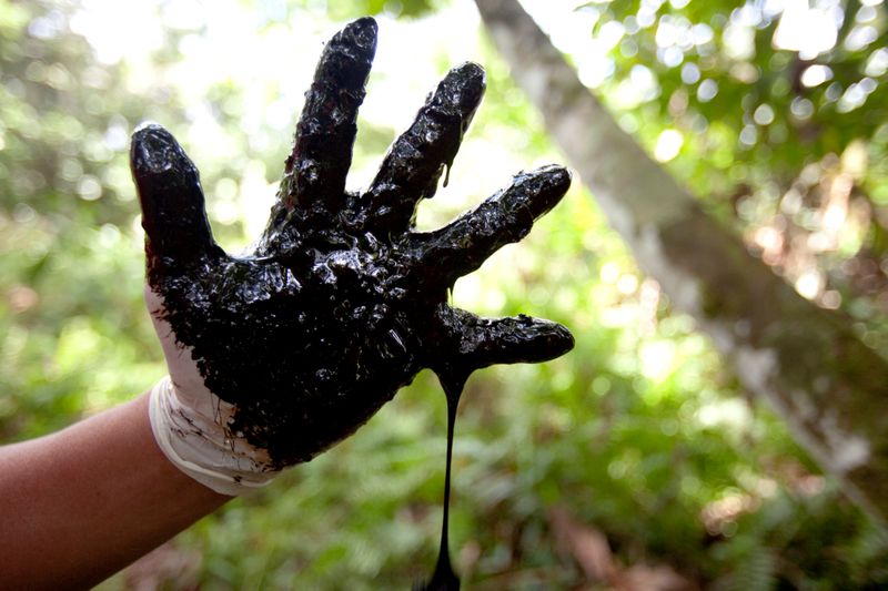 © Reuters. Membro de comunidade local mostra contaminação por petróleo em Lago Agrio, no Equador