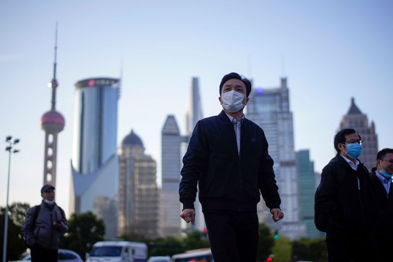 © Reuters. FILE PHOTO: FILE PHOTO: People wear protective face masks, following an outbreak of the novel coronavirus disease (COVID-19), at Lujiazui financial district in Shanghai