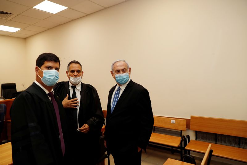 © Reuters. Israeli Prime Minister Benjamin Netanyahu, wearing a face mask, stands next to his lawyers inside the court room as his corruption trial opens at the Jerusalem District Court