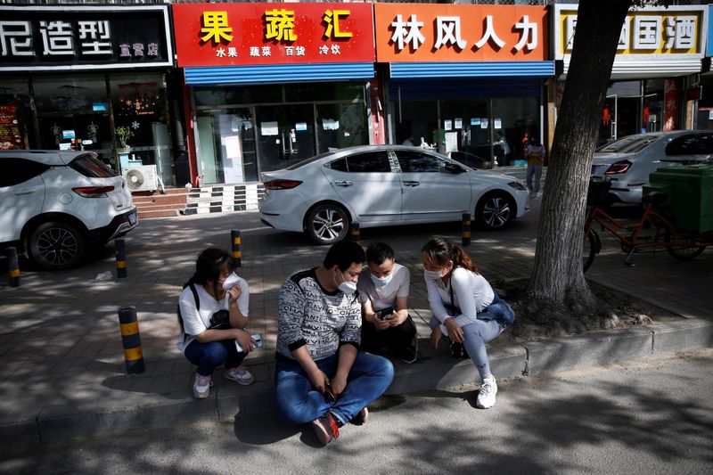 &copy; Reuters. Zhang Ruirui, Zhang Jianpeng, Guo Shengming and Zhang Yanyan sit by a street outside recruiting agencies as they browse job information on a mobile phone, in a suburb of Beijing
