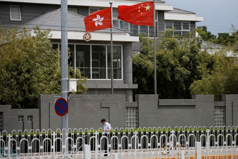 &copy; Reuters. Un hombre con una mascarilla pasando cerca de las banderas de China y  Hong Kong en Pekín