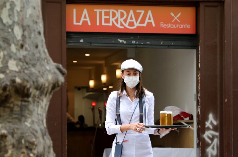 &copy; Reuters. Foto del lunes de una camarera usando máscara llevando cervezas para clientes de un restaurant en Barcelona, en medio de la pandemia de coronavirus.