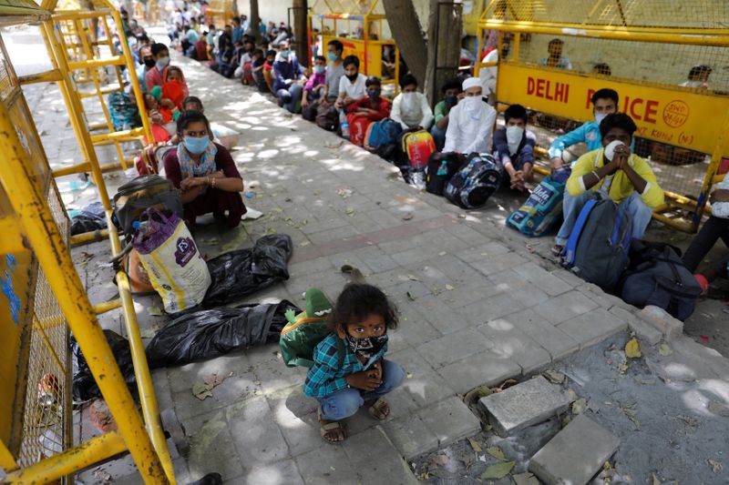 &copy; Reuters. Trabajadores migrantes y sus familias esperan a subir a un autobús para llegar a una estación de tren y volver a Uttar Pradesh, en Nueva Delhi, India, el 26 de mayo de 2020