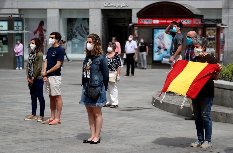 &copy; Reuters. Pessoas com máscaras de proteção durante minuto de silêncio em homenagem às vítimas de Covid-19 em Madri