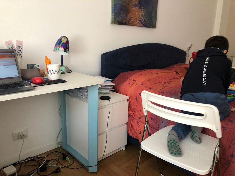 &copy; Reuters. Laura Solaro&apos;s workstation is seen at her house, while her son Niccolo climbs onto the bed to play, in Milan