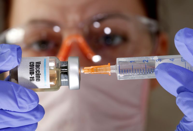 &copy; Reuters. FILE PHOTO: A woman holds a small bottle labeled with a &quot;Vaccine COVID-19&quot; sticker and a medical syringe in this illustration