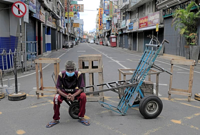 &copy; Reuters. FILE PHOTO: A labourer sits on a cart in a street with closed shops near the main market on labour day, during a curfew amid concerns about the spread of coronavirus disease (COVID-19), in Colombo