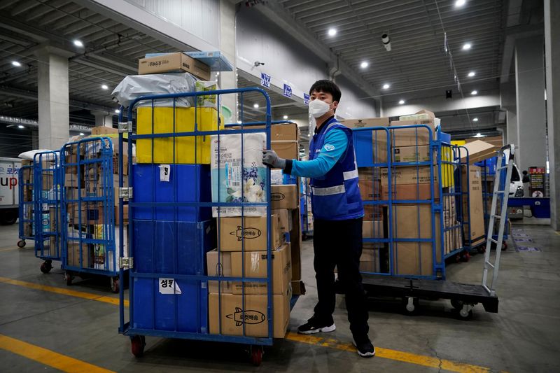 &copy; Reuters. FILE PHOTO: File picture of a delivery man for Coupang wearing a mask loading packages