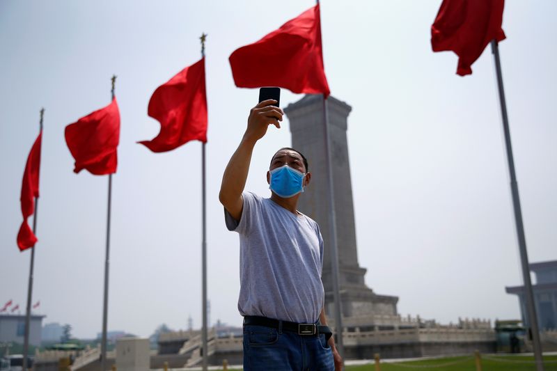 &copy; Reuters. Visitante posa para foto em Pequim com bandeira da China ao fundo