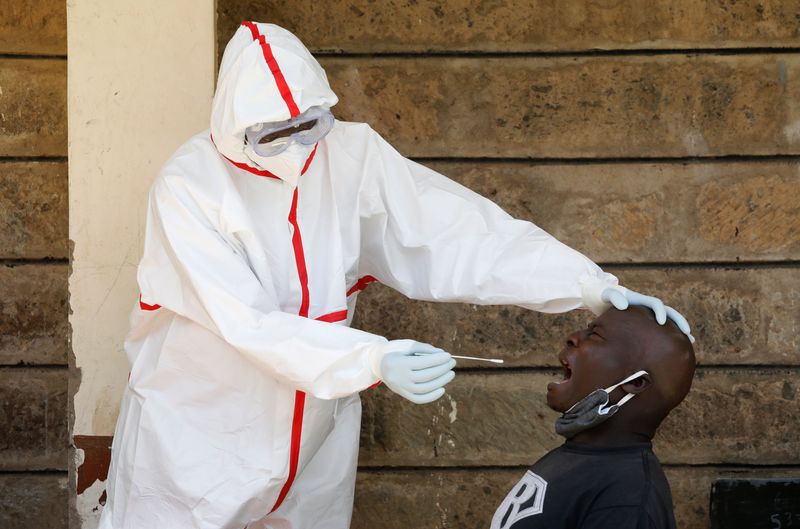 &copy; Reuters. Profissional de saúde com trajes de proteção coleta amostra de paciente para exame de detecção de Covid-19 em Nairóbi