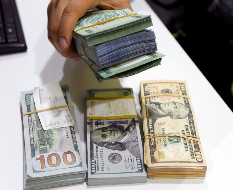 &copy; Reuters. FILE PHOTO: A man holds Lebanese pounds next to U.S. dollar banknotes at a currency exchange shop in Beirut