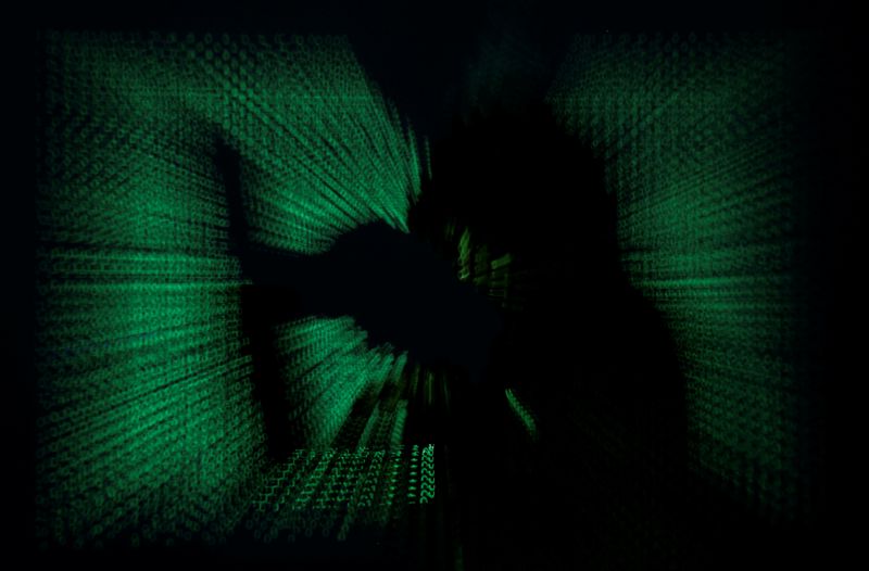 &copy; Reuters. FILE PHOTO:  Hooded man holds laptop computer as cyber code is projected on him in this illustration picture