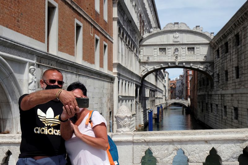 &copy; Reuters. Turistas com máscara de proteção posam para foto em ponte de Veneza