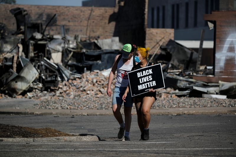 &copy; Reuters. Protesters wearing face masks walk with a Black Life Matters sign in Minneapolis