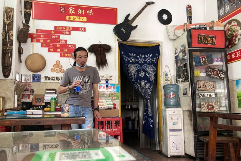 © Reuters. Noodles shop owner and a rock band singer Wang Zongxing stands inside his shop in Shenzhen