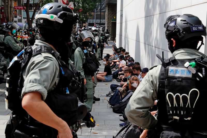 &copy; Reuters. Anti-government demonstrators sit as they were detained during a lunch time protest as a second reading of a controversial national anthem law takes place in Hong Kong