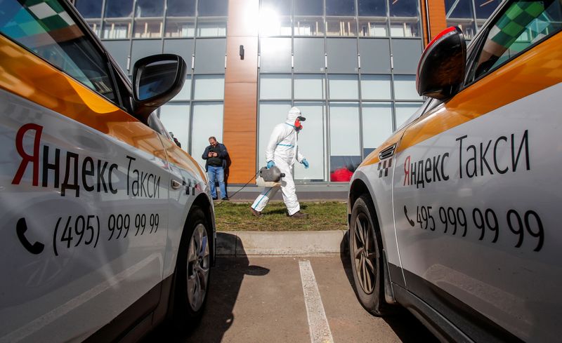 &copy; Reuters. Специалист в защитном костюме дезинфицирует автомобили водителей, сотрудничающих с сервисом Яндекс.Такси, в Москве