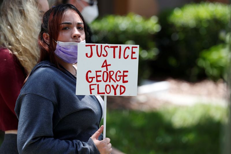 &copy; Reuters. Una manifestante sostiene un cartel afuera de la casa de Florida del exoficial de policía de Minneapolis Derek Chauvin, quien fue grabado con una rodilla en el cuello del hombre afroamericano George Floyd antes de su muerte, en el vecindario Windermere d