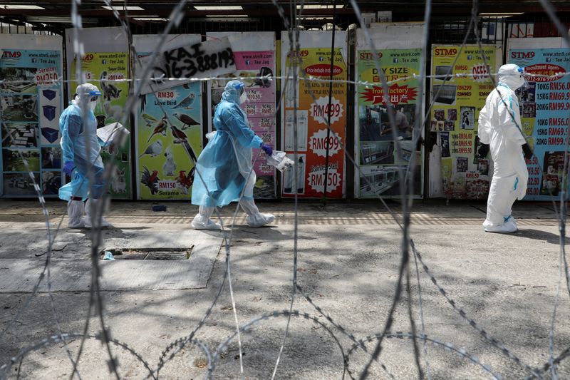 &copy; Reuters. FILE PHOTO: Medical workers wearing protective suits pass by barbed wire at the red zone under enhanced lockdown, amid the coronavirus disease (COVID-19) outbreak, in Petaling Jaya