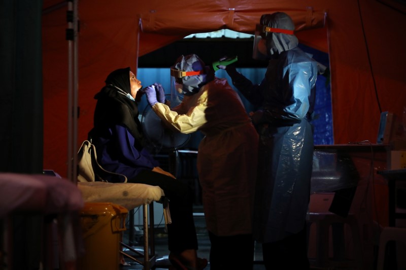 &copy; Reuters. FILE PHOTO: Health workers get a swab from a woman in a makeshift centre tent set up in the Kuala Lumpur Hospital parking lot, amid the coronavirus disease (COVID-19) outbreak, in Kuala Lumpur