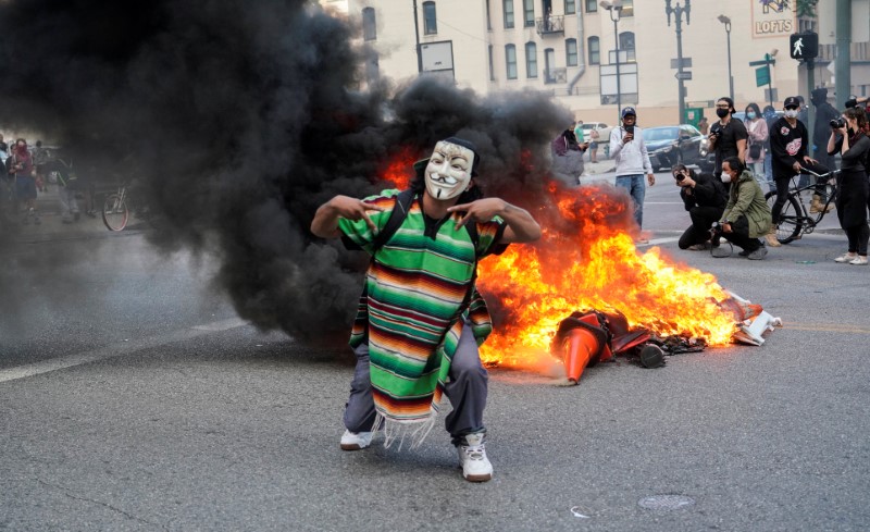 © Reuters. Un manifestante enmascarado se para frente al fuego, en Los Ángeles, California