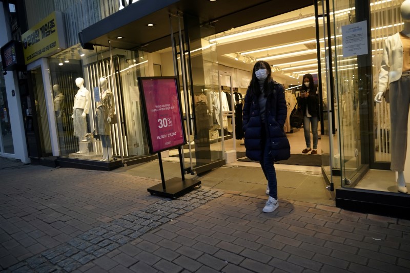 &copy; Reuters. FILE PHOTO: Women wearing masks to prevent contracting the coronavirus walks out of a shop at Dongseong-ro shopping street in central Daegu