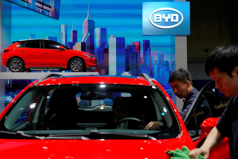 © Reuters. FILE PHOTO: Men clean a BYD electric vehicle (EV) e2 displayed during the media day for Shanghai auto show