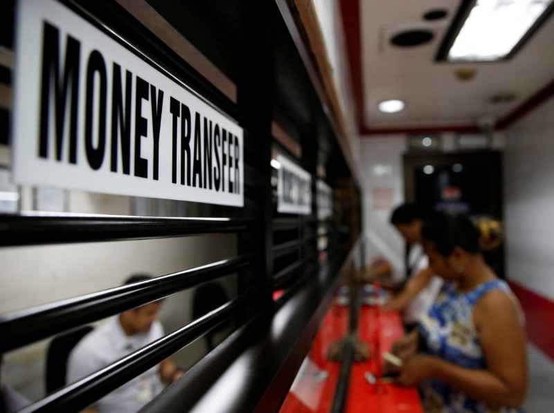 © Reuters. FILE PHOTO: Customers receive money from families working abroad at a money remittance center in Makati