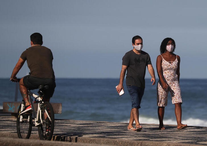 &copy; Reuters. Casal com máscara de proteção caminha perto da praia do Leblon, no Rio de Janeiro