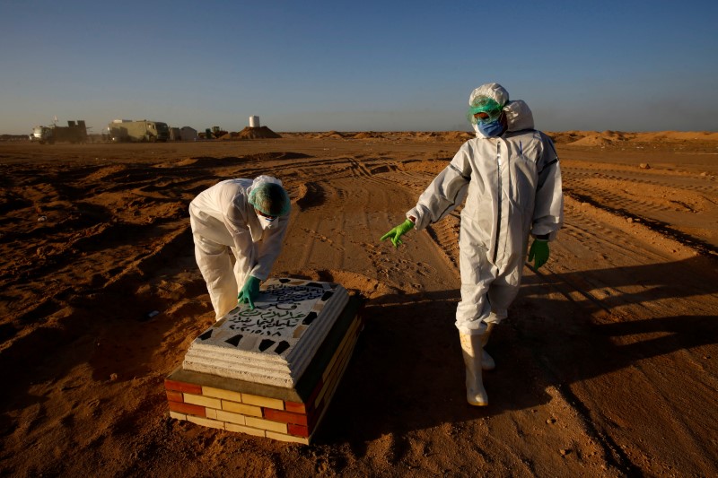 &copy; Reuters. Members of the Popular Mobilization Forces (PMF) bury people who passed away due to coronavirus disease (COVID-19) at the new Wadi Al-Salam cemetery on the outskirts of the holy city of Najaf