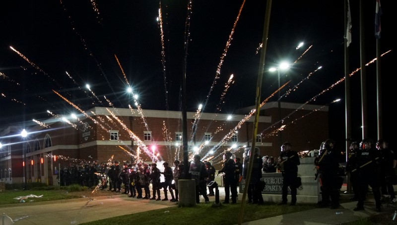 &copy; Reuters. Fogos de artifício explodem atrás de policiais durante protesto em Ferguson, Missouri